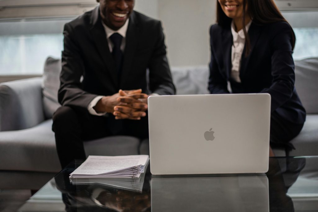 Professional two-person team having a discussion in an office setting with laptop.